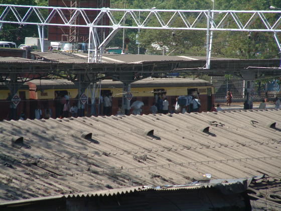 Looking over a corrugated roof to an Indian commuter train